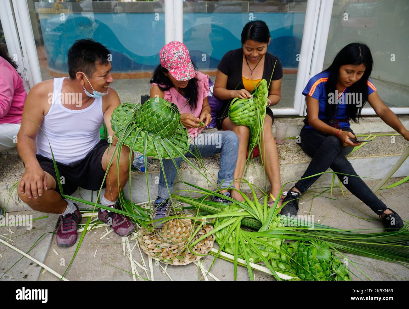 Membres de la famille qui font des chapeaux de feuilles de palmier à noix de coco, Acapulco, Mexique Banque D'Images