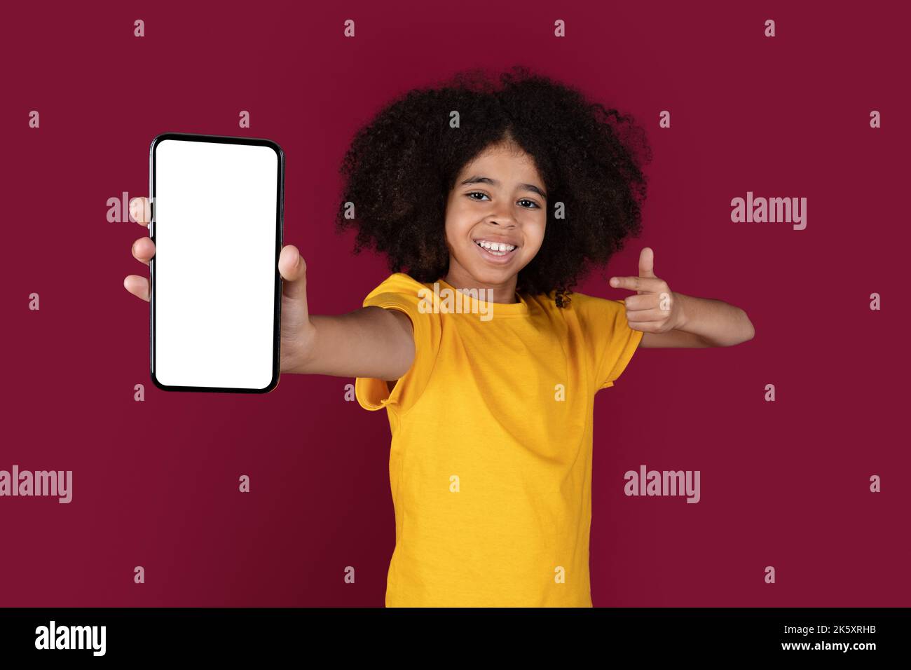 Joyeux enfant noir pointant vers le téléphone portable, mockup Banque D'Images