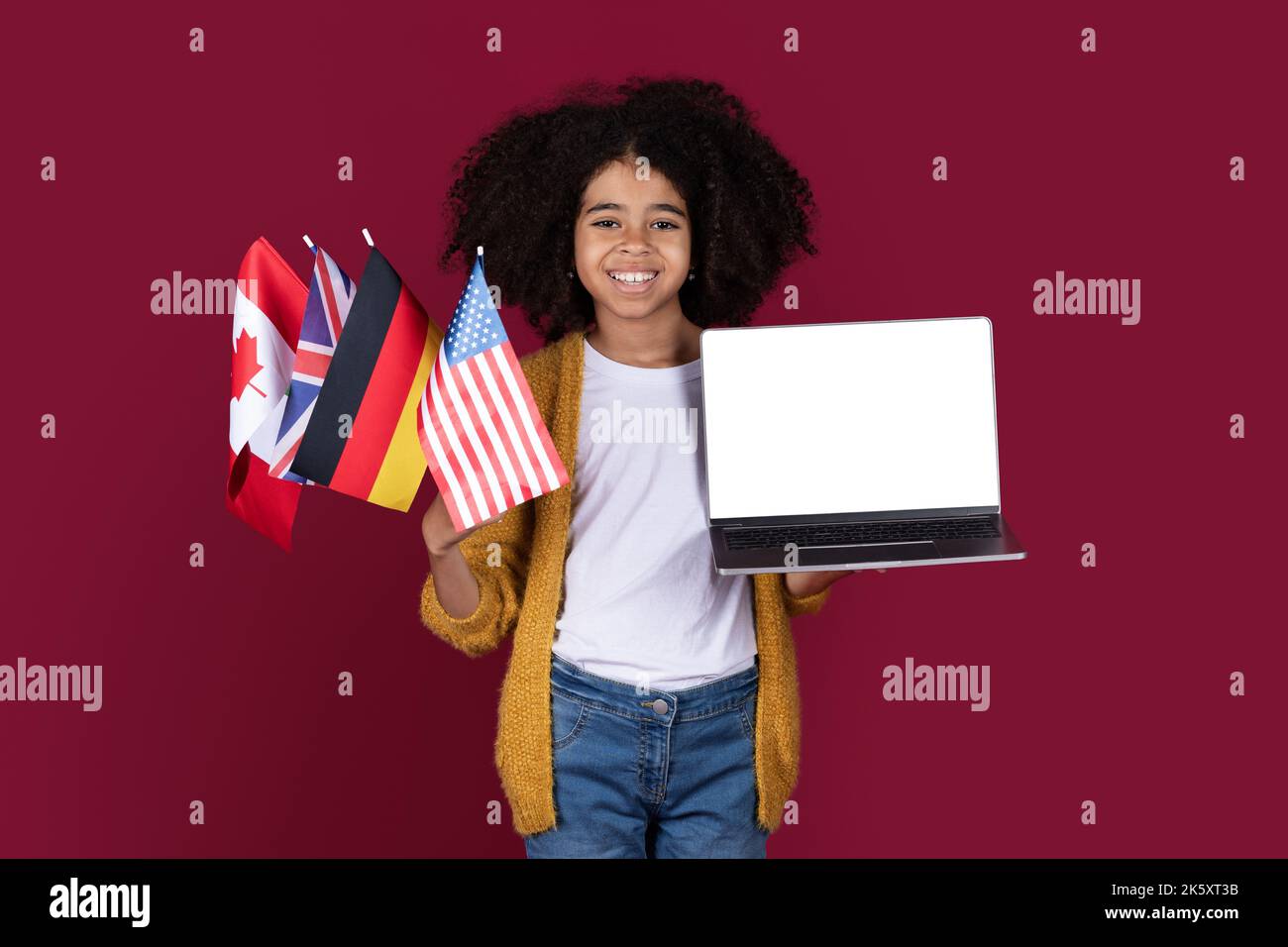 Joyeux enfant noir tenant un ordinateur portable et un bouquet de drapeaux Banque D'Images
