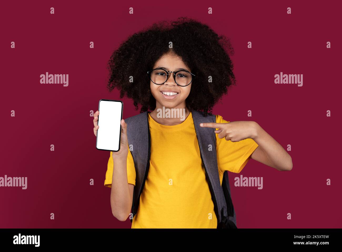 Bonne fille noire écolière montrant smartphone, maquette Banque D'Images