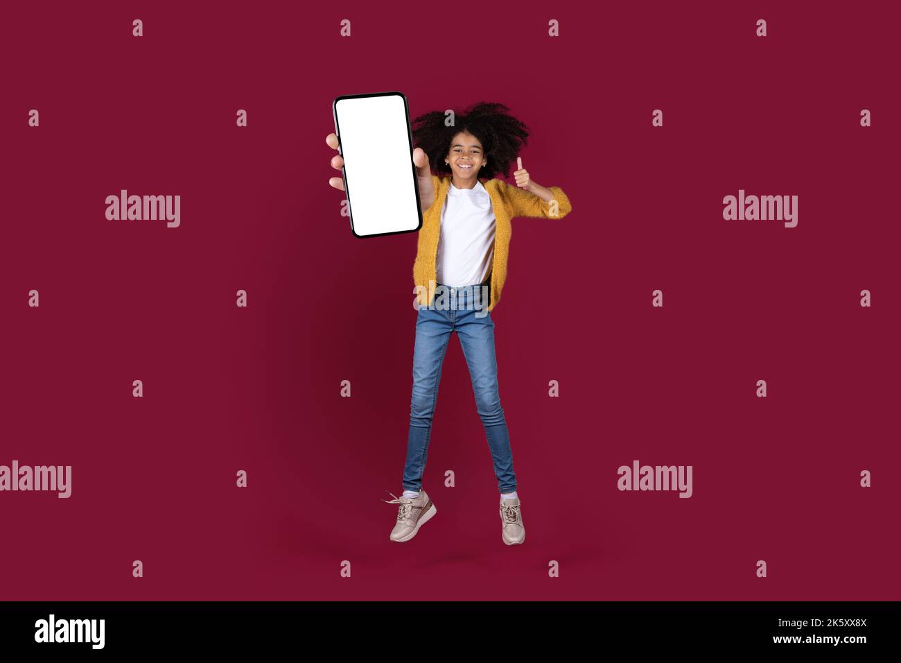 Joyeux enfant afro-américain sautant avec un smartphone, mockup Banque D'Images