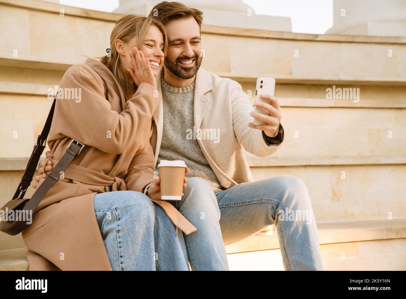 Couple romantique blanc riant et prenant le selfie sur le téléphone portable pendant la date à l'extérieur Banque D'Images
