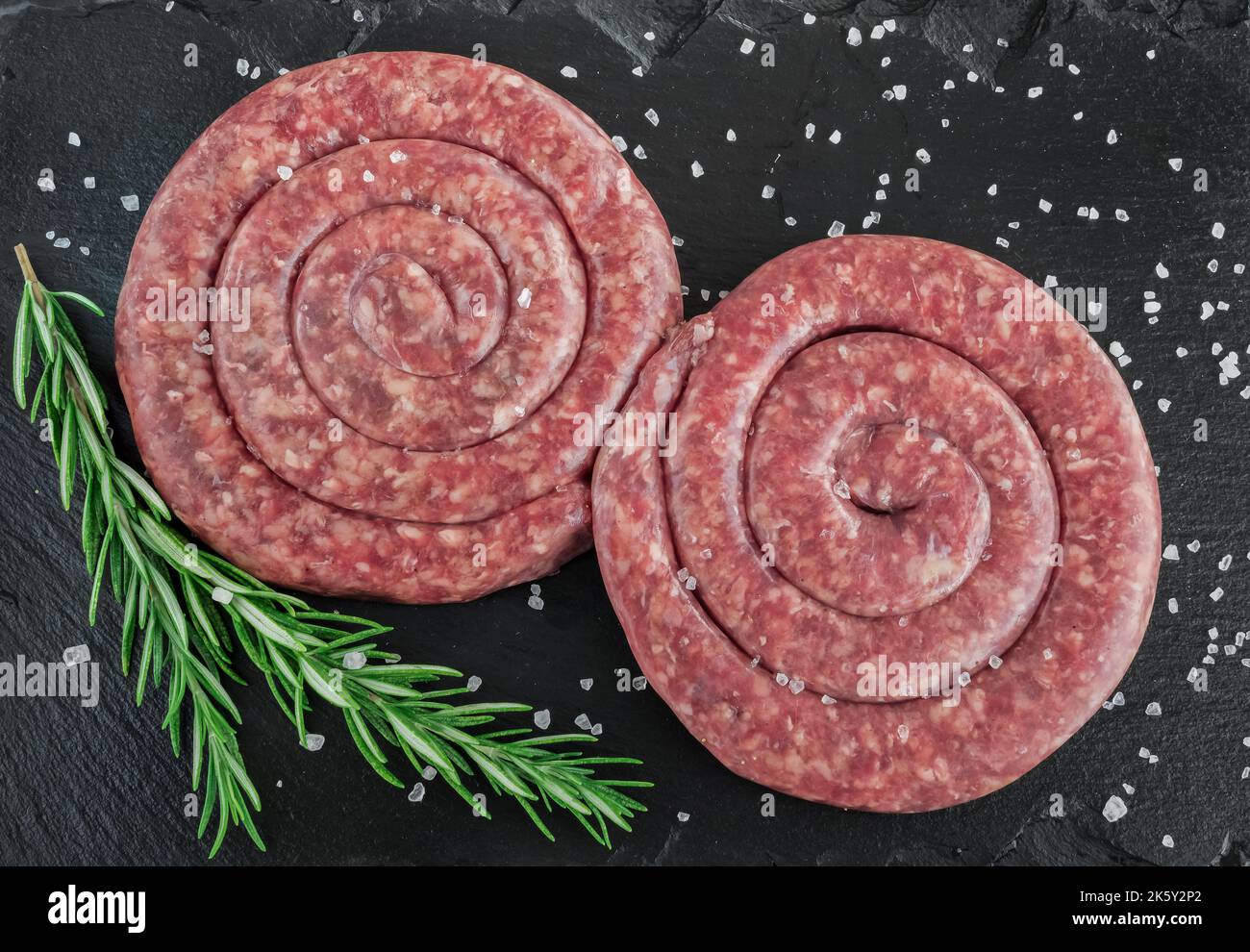 Saucisse de porc en spirale sur panneau noir Banque D'Images