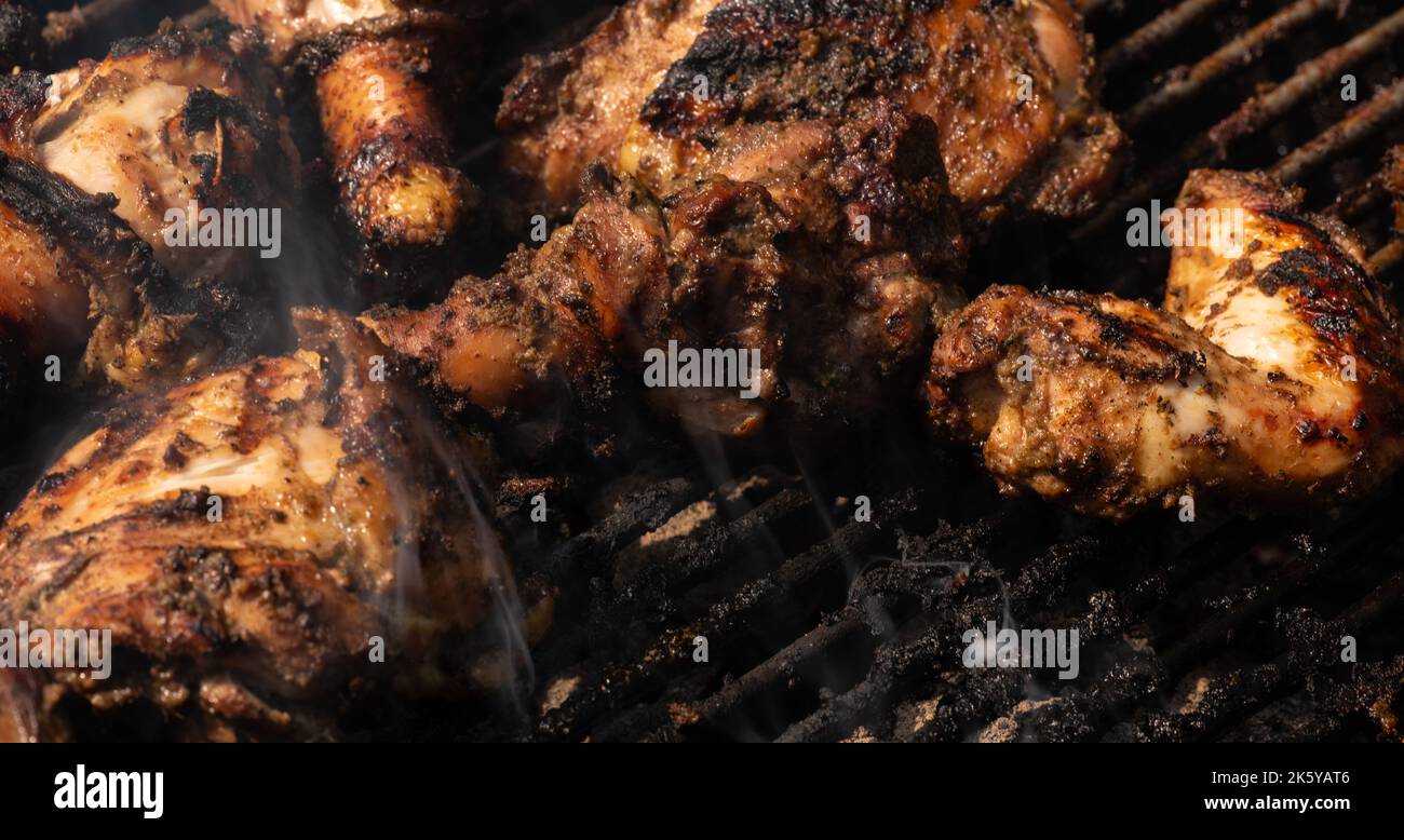 Griller le poulet traditionnel jamaïcain épicé avec plus de feu de charbon de bois. Banque D'Images