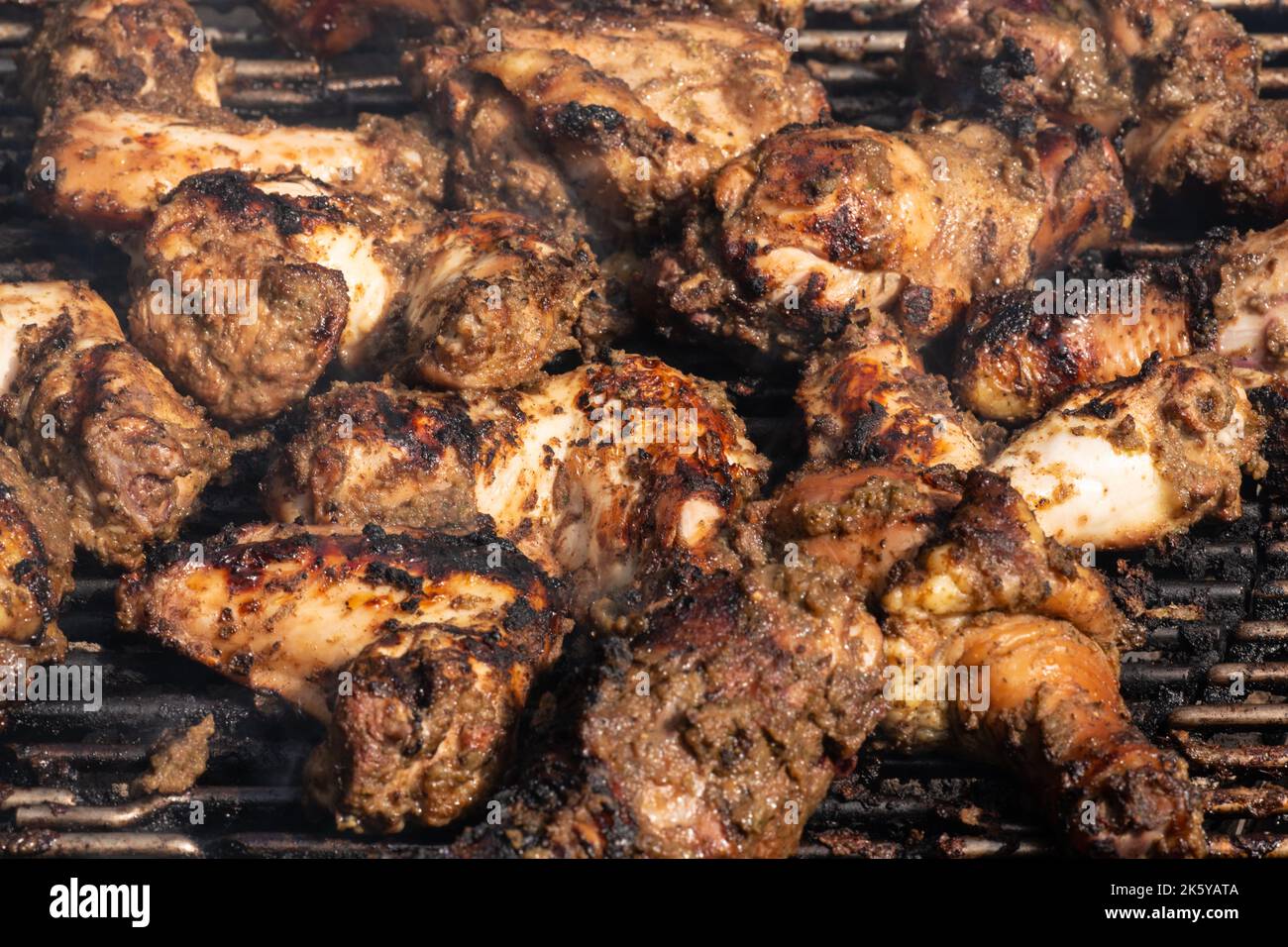 Griller le poulet traditionnel jamaïcain épicé avec plus de feu de charbon de bois. Banque D'Images