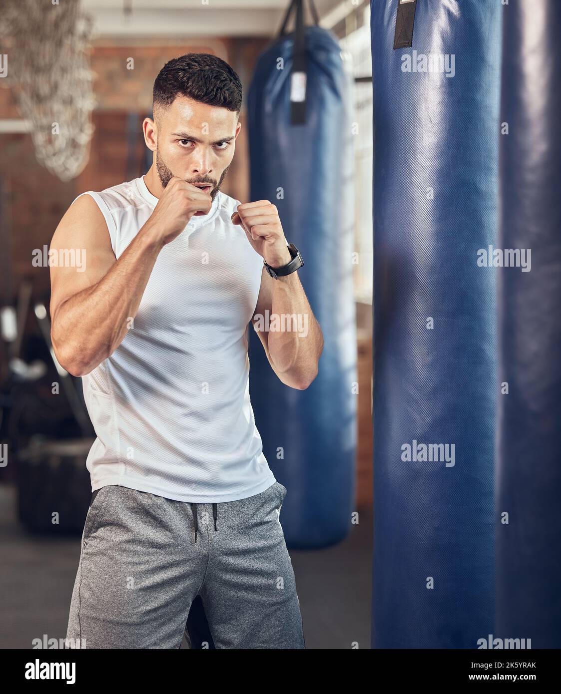 Boxer résistant prêt à frapper dans la salle de gym. Portrait du combattant mma prêt pour le combat cardio. Boxer s'y portant avec un sac de poinçonnage. Bodybuilder à l'aide de Banque D'Images
