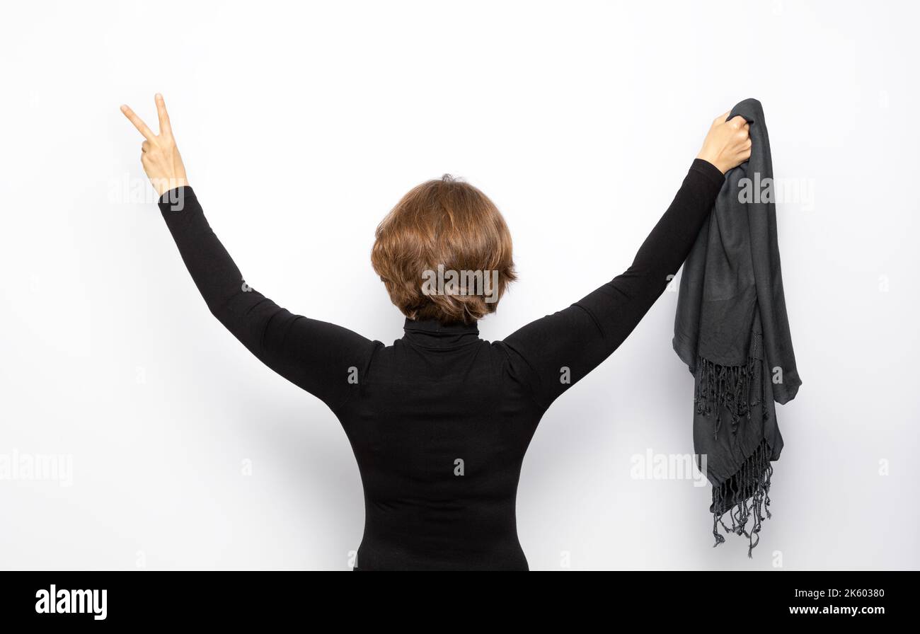 Un manifestant féminin iranien tient un hijab dans sa main et montre un signe de victoire. Banque D'Images