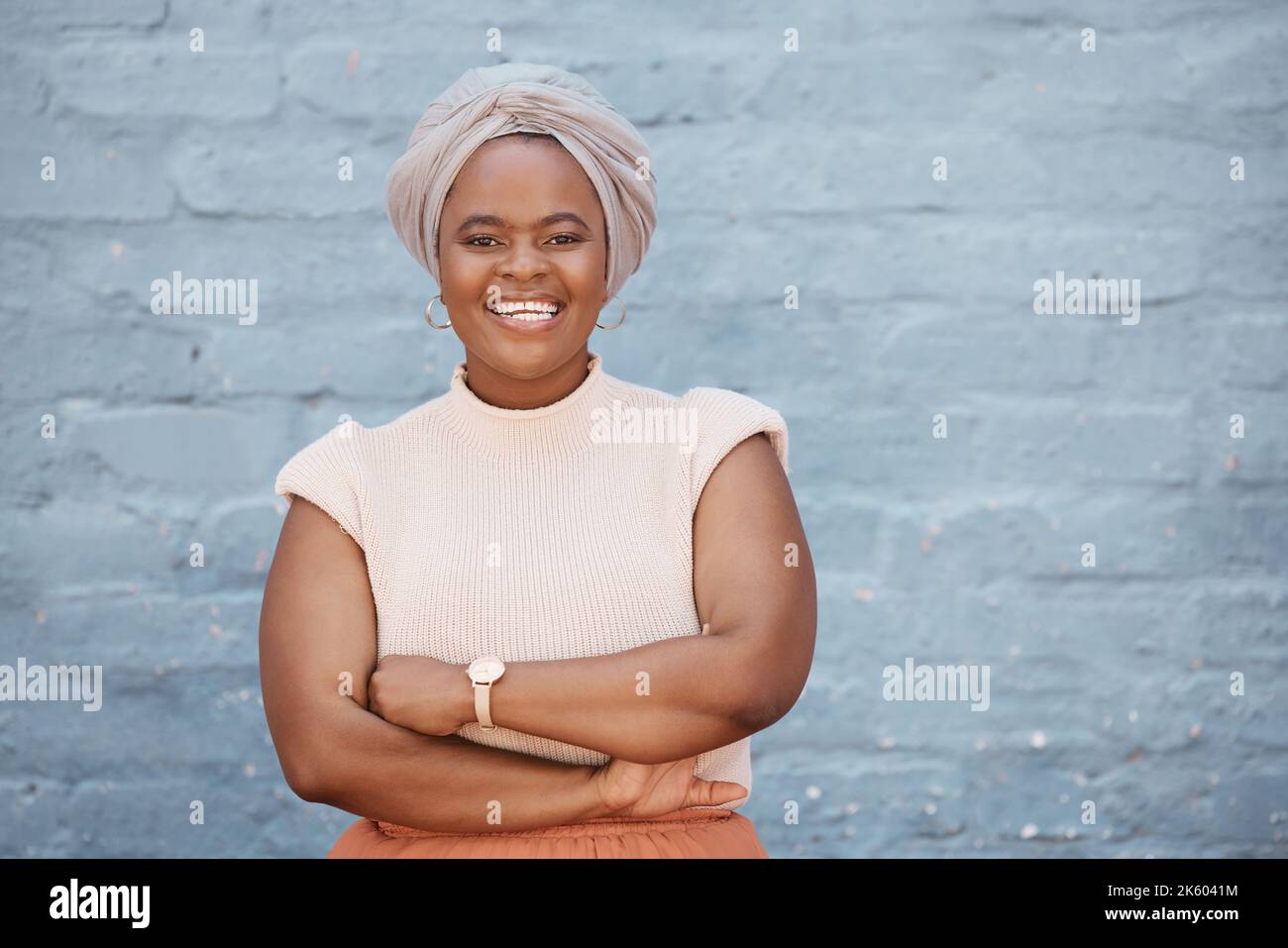 Une femme d'affaires afro-américaine souriante avec un foulard posant avec les bras croisés sur un fond gris. Portrait de confiant, réussi Banque D'Images