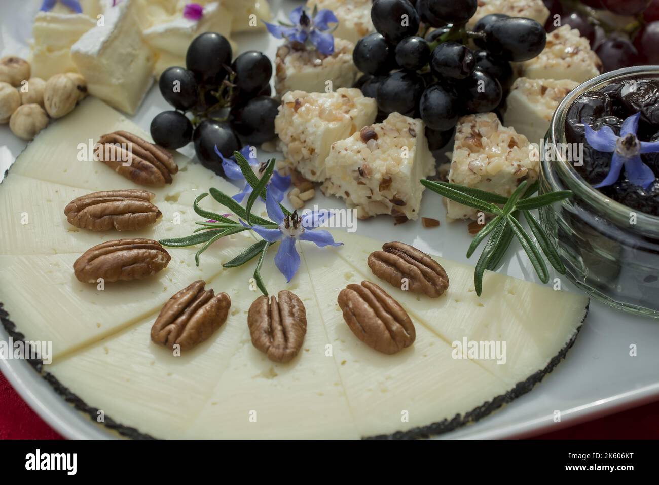 sélection de fromages avec raisins et fleurs comestibles Banque D'Images