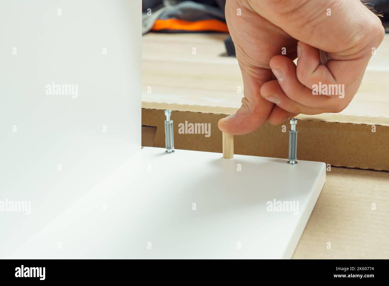 Main mâle doigt cheville en bois pour fixer les murs de tiroir blanc, l'assemblage de commode ou de garde-robe sur le sol. Attaches de meubles excentriques sur les côtés. Auto-assemblage Banque D'Images