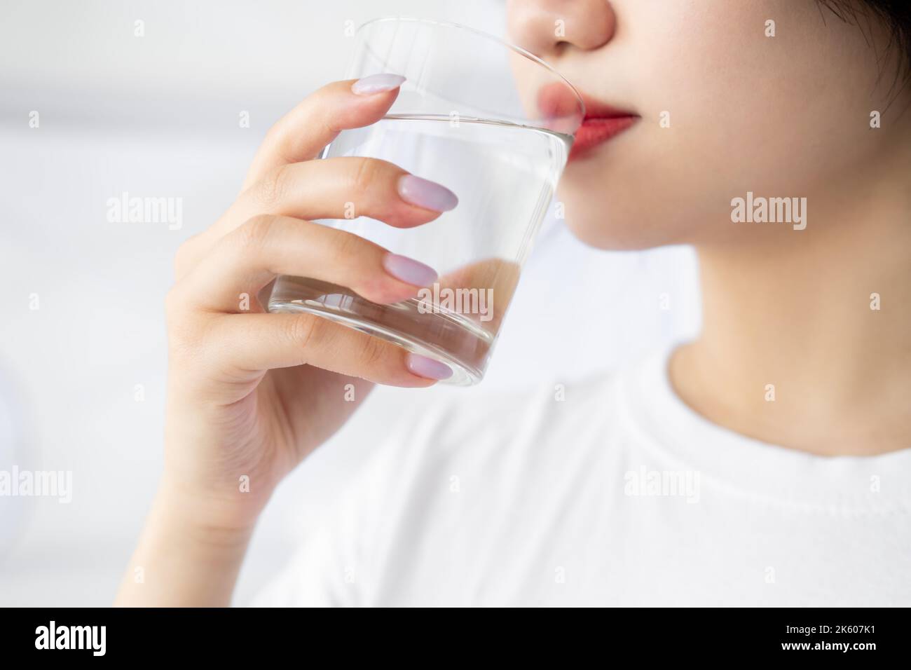 Équilibre de l'eau. Femme asiatique. Soins de beauté du matin. Traitement nourrissant. Une femme japonaise méconnue boit une boisson propre dans une pièce lumineuse. Banque D'Images