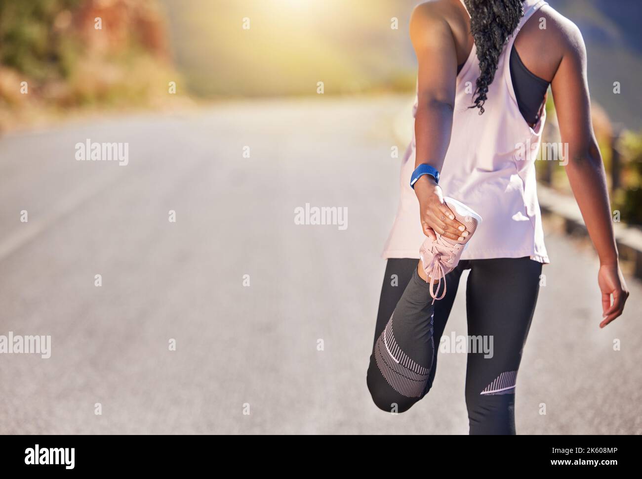 Gros plan sur une athlète afro-américaine qui s'étire avant une course à l'extérieur sur une route. L'exercice est bon pour votre santé et votre bien-être. L'étirement, c'est Banque D'Images