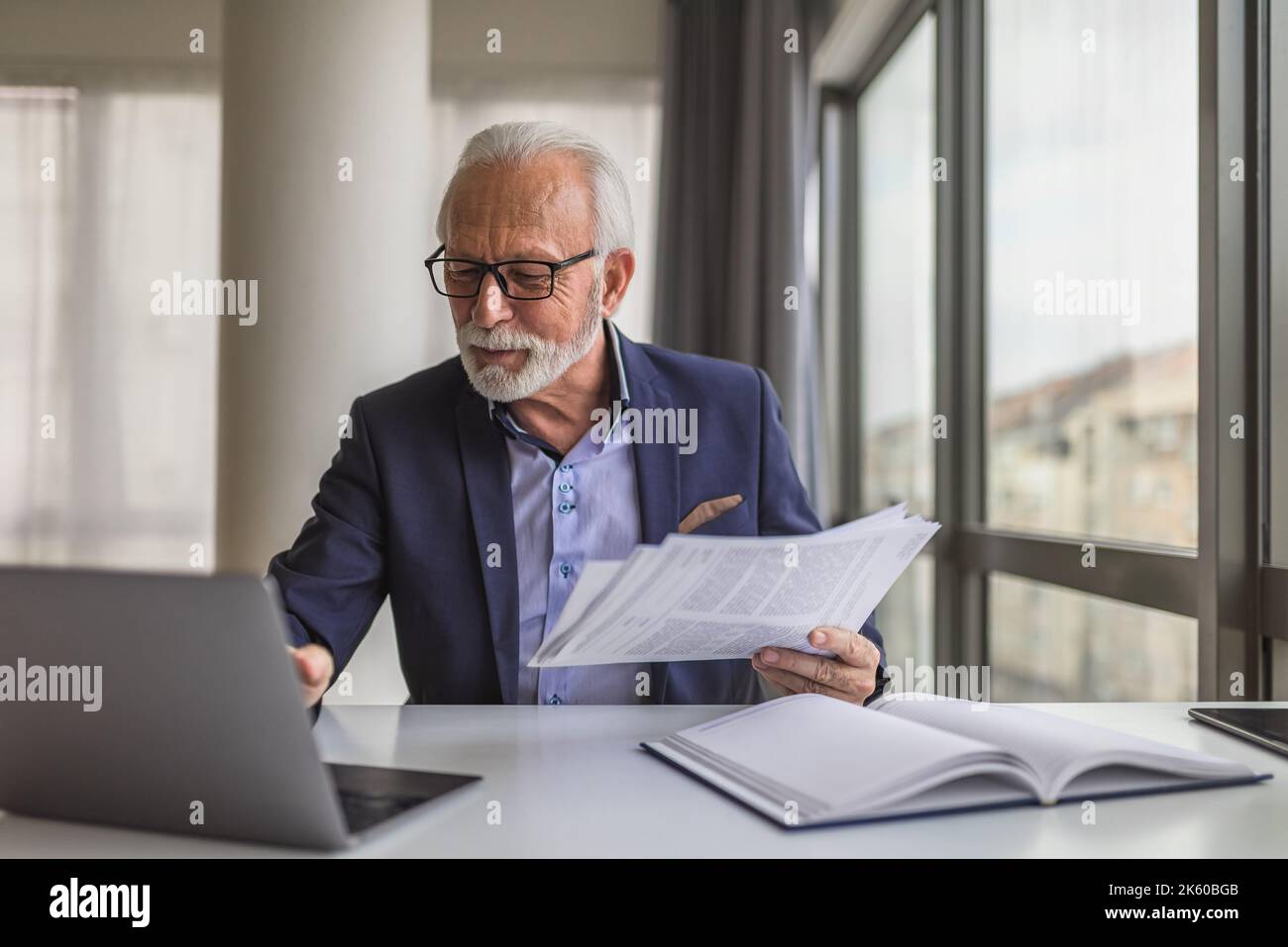 Barbu entrepreneur principal avec des lunettes, en vérifiant son calendrier de travail sur son ordinateur portable, à la salle de réunion. Banque D'Images