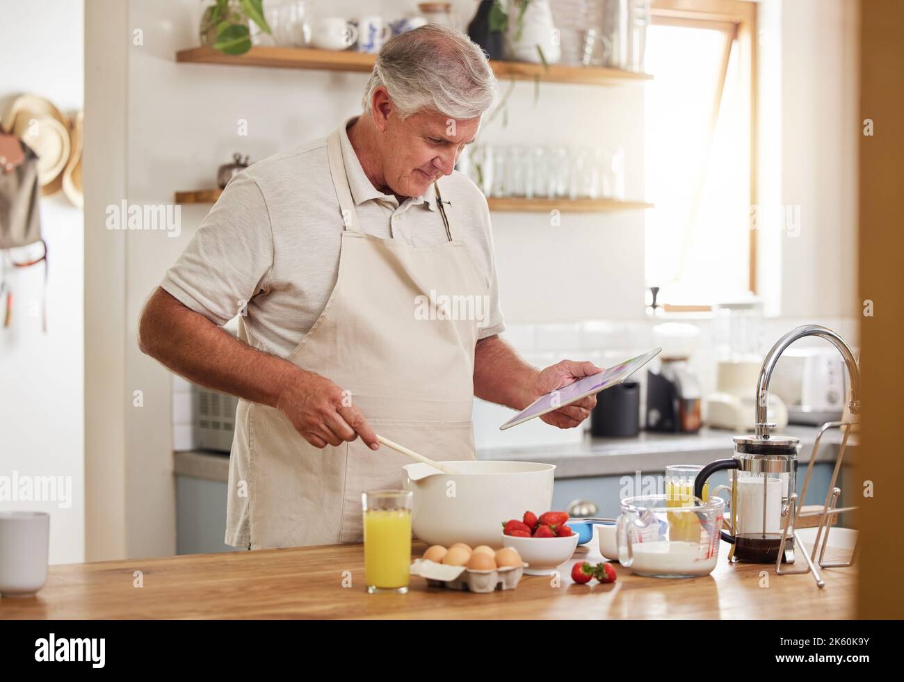 Cuisine, recette et homme senior avec une vidéo en ligne pour le petit déjeuner dans la cuisine de sa maison. Homme âgé lisant des informations sur la nourriture pour la santé Banque D'Images