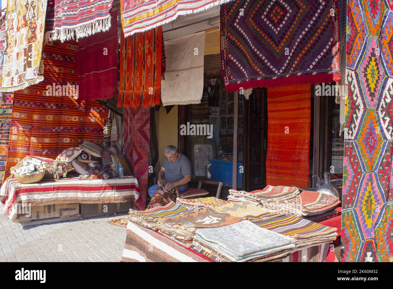 Homme tissage de tapis fait à la main devant son magasin traditionnel, homme de couture de tapis traditionnel Banque D'Images