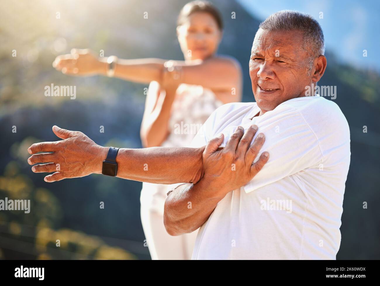 Homme âgé étirant ses bras tout en faisant de l'exercice à l'extérieur par une journée ensoleillée. Personnes matures pratiquant le yoga ensemble dans la nature rester en bonne santé et actif Banque D'Images