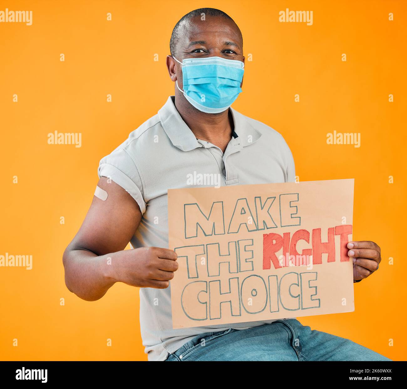 Homme vacciné Covid afro-américain montrant du pansement pour bras, tenant une affiche et portant un masque chirurgical. Modèle noir isolé sur studio jaune Banque D'Images