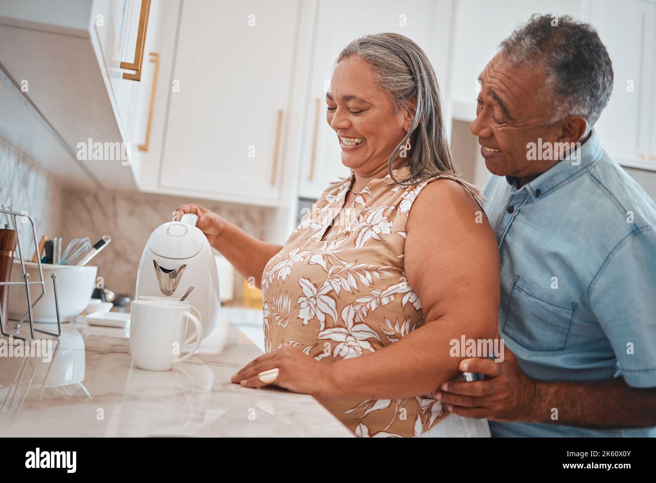 Thé, couple et retraite avec un homme et une femme utilisant une bouilloire dans la cuisine de leur maison ensemble. Amour, matin et romance avec un homme âgé et Banque D'Images