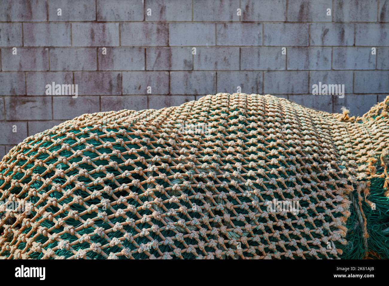 Une pile de filets de pêche placés contre un mur de briques le jour de soleil dans le port Banque D'Images