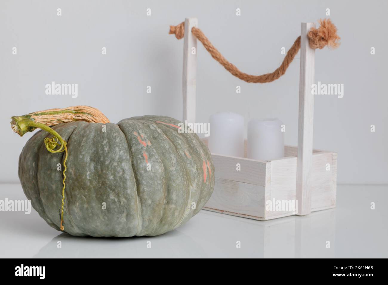 Composition minimaliste automnale de citrouille et de bougies sur une table blanche. Concept de célébration de Thanksgiving et Halloween. Banque D'Images