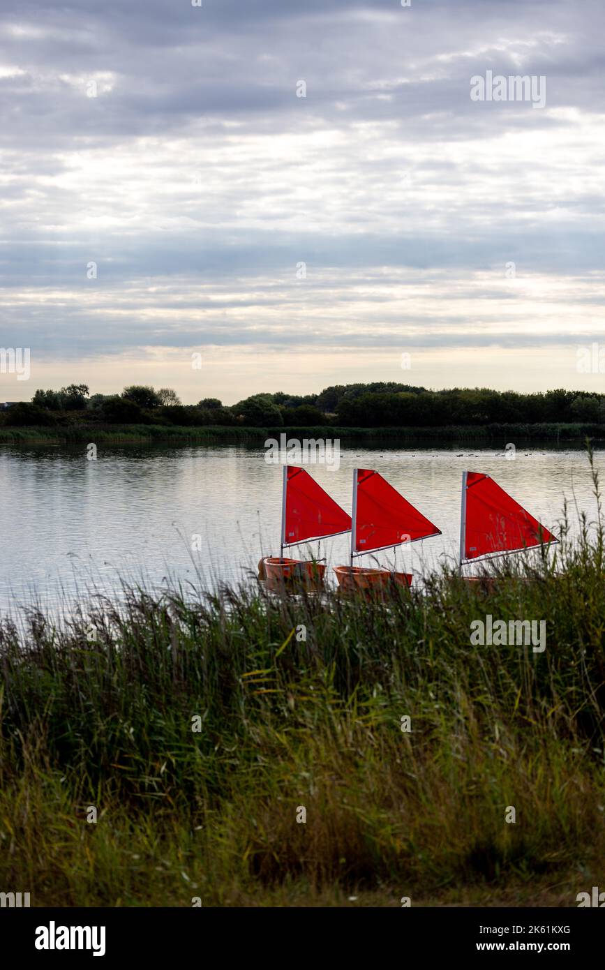 Petits bateaux avec voiles rouges sur un lac Banque D'Images