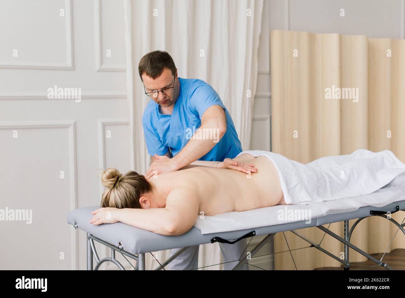 Une jeune femme de gras reçoit un massage dans un cabinet de spa de jour. Banque D'Images