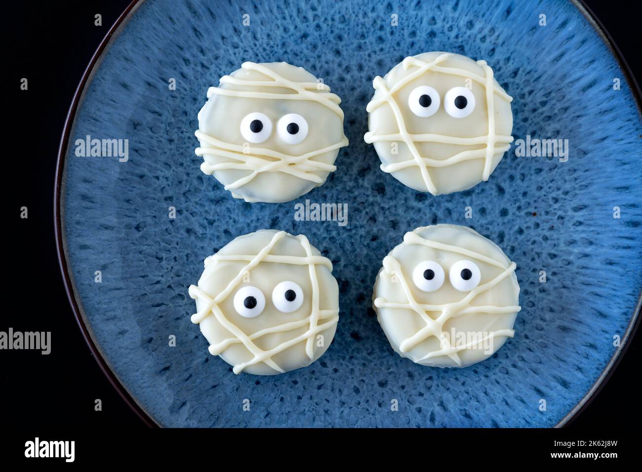 Biscuits Mummy égyptiens effrayants. Les friandises d'Halloween sont faites maison à l'aide de chocolat blanc fondu sur des biscuits Oreo. Les yeux comestibles complètent les biscuits Banque D'Images