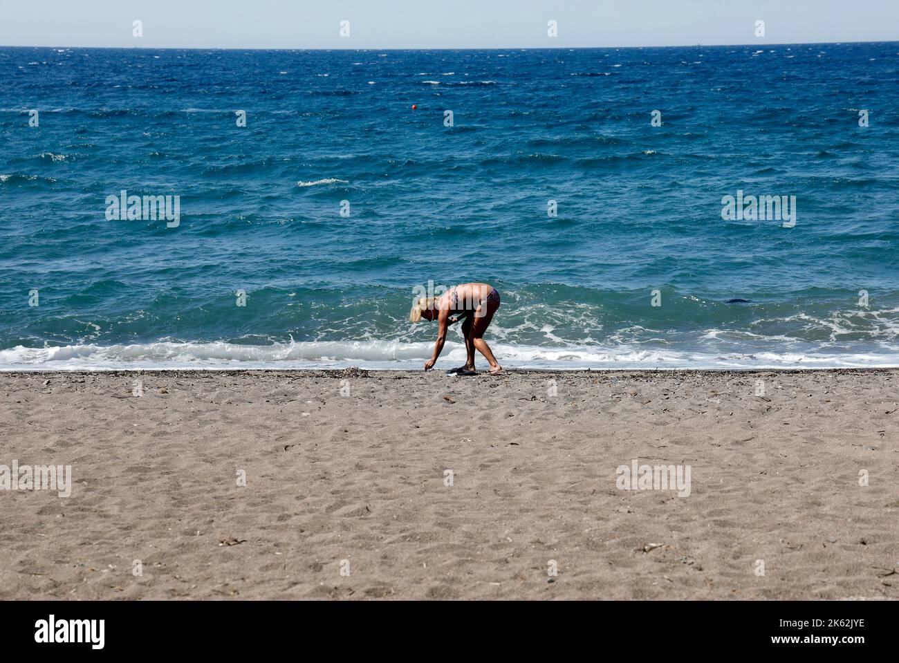 Femme en train de se baladerer avec la mer bleue derrière. Lesvos (Lesbos/Mitylène) . Septembre 2022. Scène d'été. Banque D'Images