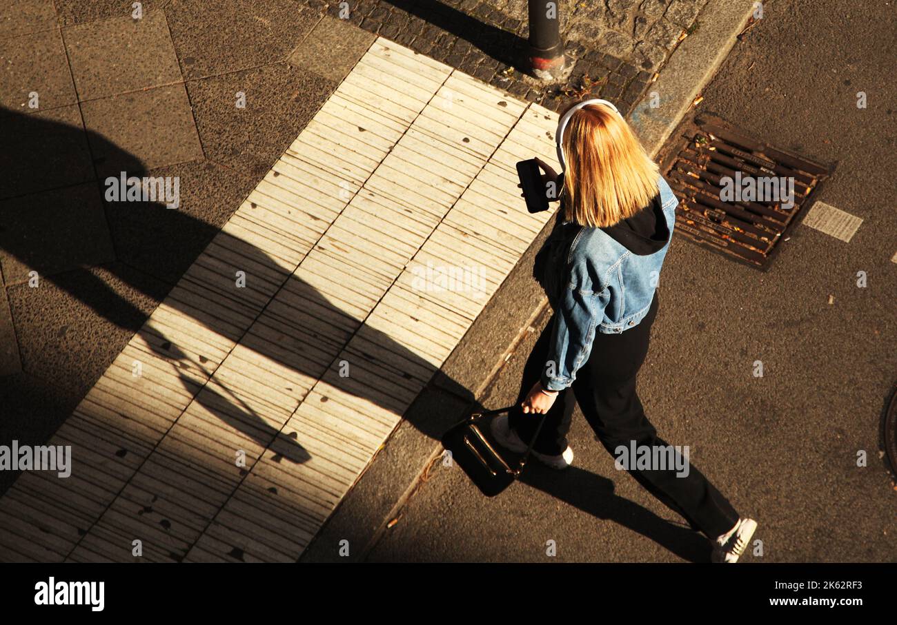 Berlin, Allemagne. 06th octobre 2022. 06.10.2022, Berlin. Une jeune femme porte un casque et regarde son smartphone tout en traversant une rue à Steglitz. Crédit: Wolfram Steinberg/dpa crédit: Wolfram Steinberg/dpa/Alay Live News Banque D'Images