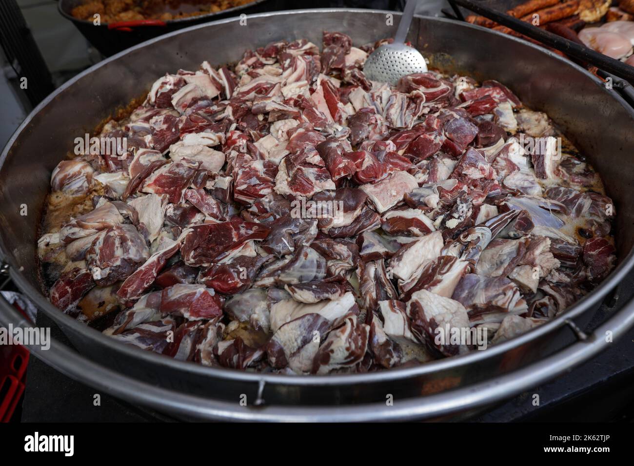 Détails de faible profondeur de champ (mise au point sélective) avec cuisson de viande d'agneau sur une grande casserole en métal. Banque D'Images