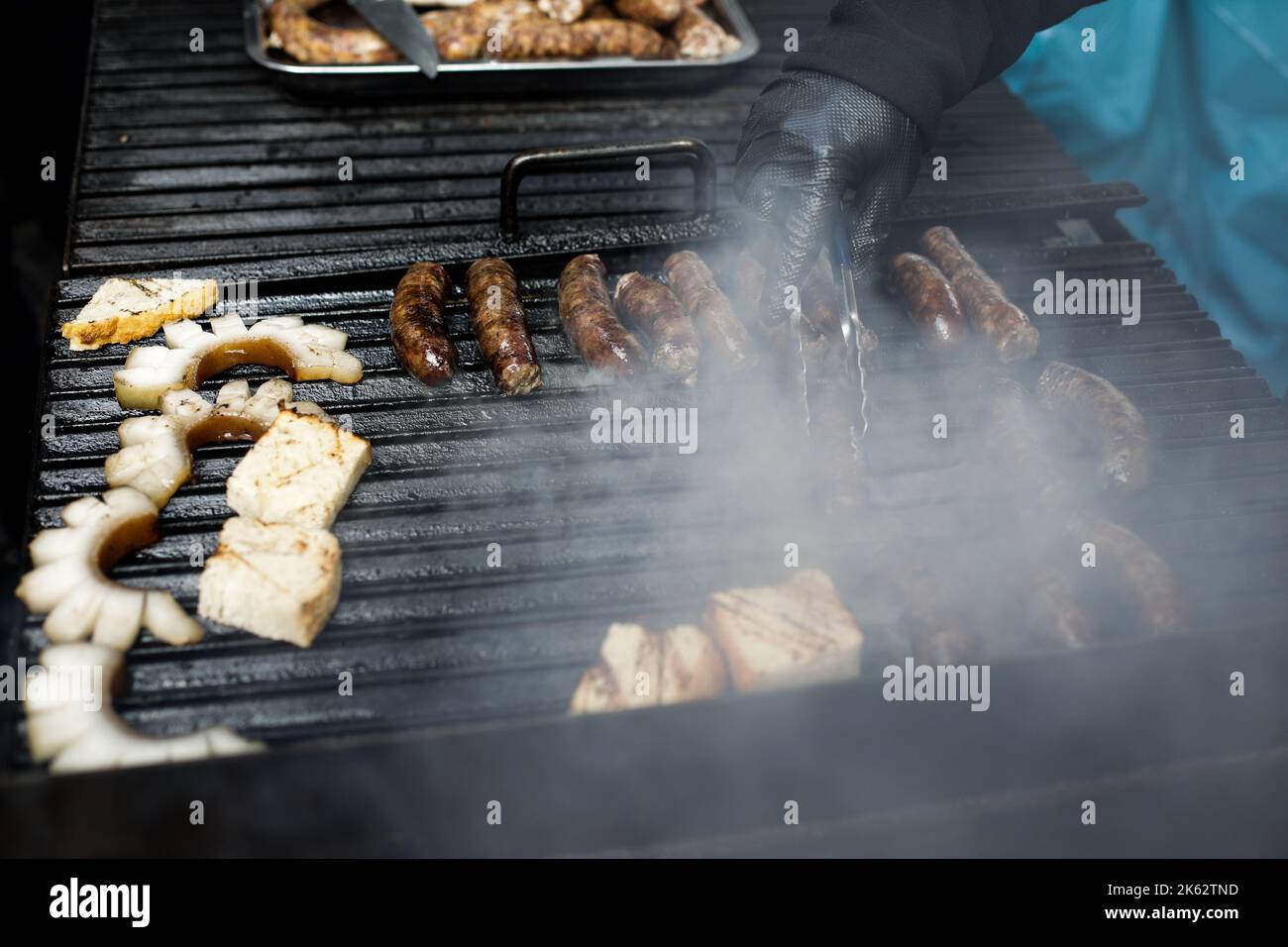 Détails de faible profondeur de champ (mise au point sélective) avec des saucisses de porc cuisant sur un barbecue, sur un marché agricole européen. Banque D'Images