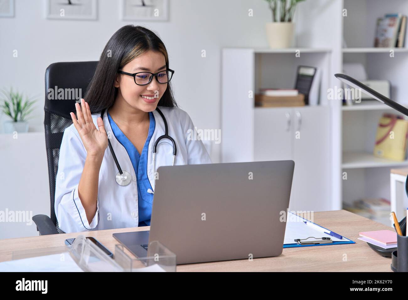 Jeune femme asiatique médecin saluant le patient pendant la vidéoconférence Banque D'Images