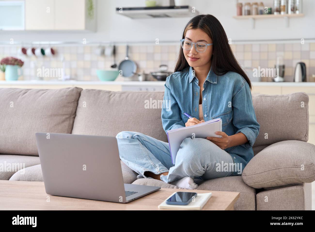 Femme asiatique adolescente regardant un webinaire sur un ordinateur portable pour prendre des notes Banque D'Images