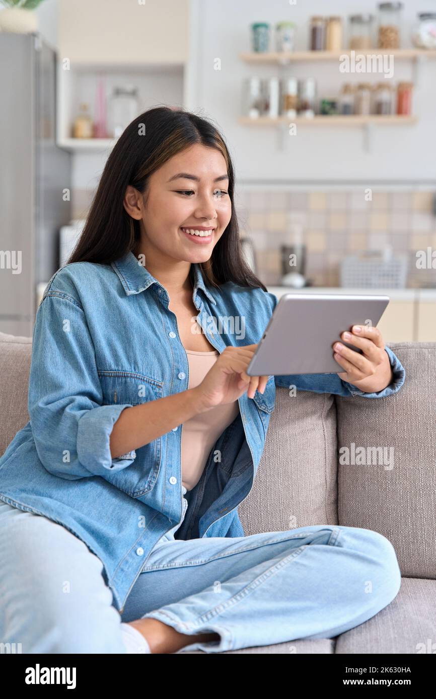 Jeune femme asiatique décontractée utilisant une tablette numérique se détendre à la maison Banque D'Images