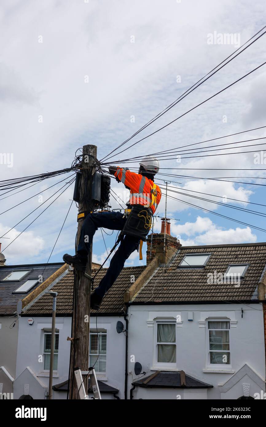 Ingénieur en télécommunications travaillant au sommet d'un poteau téléphonique. Banque D'Images
