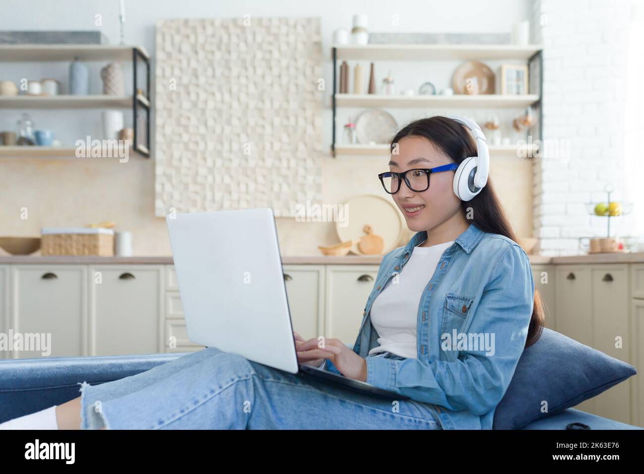 Femme asiatique assise sur un canapé à la maison à l'aide d'un ordinateur portable pour regarder des vidéos éducatives, étudiant étudiant étudiant à distance en ligne. Banque D'Images