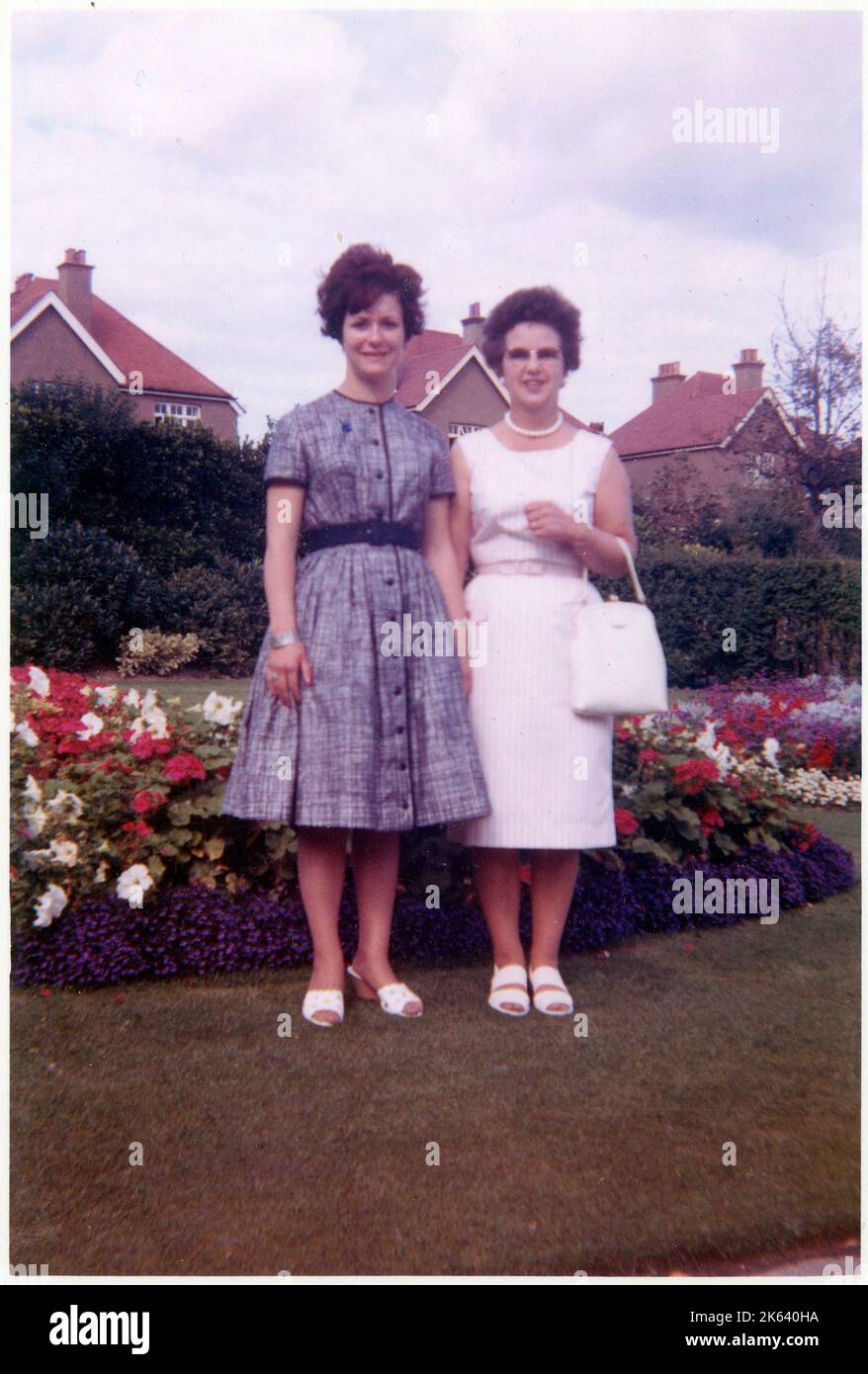 Une mère et une fille debout dans un magnifique jardin arrière de banlieue britannique, bien entretenu, devant des parterres de fleurs colorées - septembre 1962 Banque D'Images
