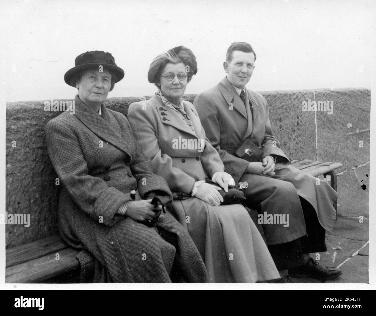 Deux femmes matures avec un homme plus jeune posent pour un claquement sur un banc le long du front de mer dans une station britannique non identifiée. Banque D'Images