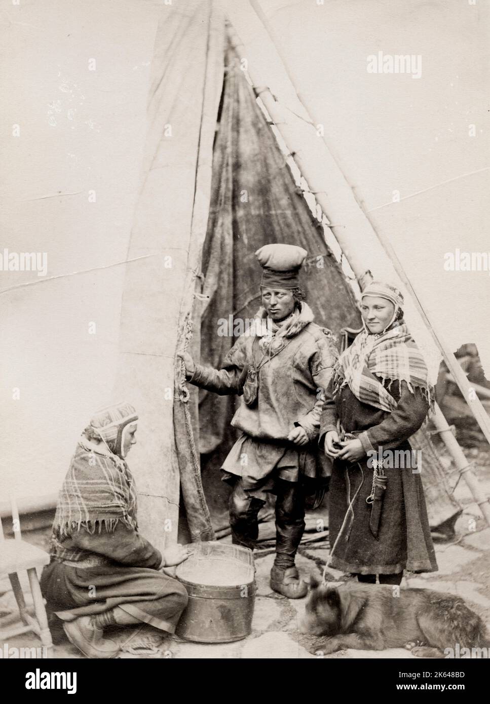 Photographie vintage du XIXe siècle: Les Sâmes et leur chien à l'extérieur d'une tente Finnmarken, Norvège. Studio Axel Lindahl. Banque D'Images