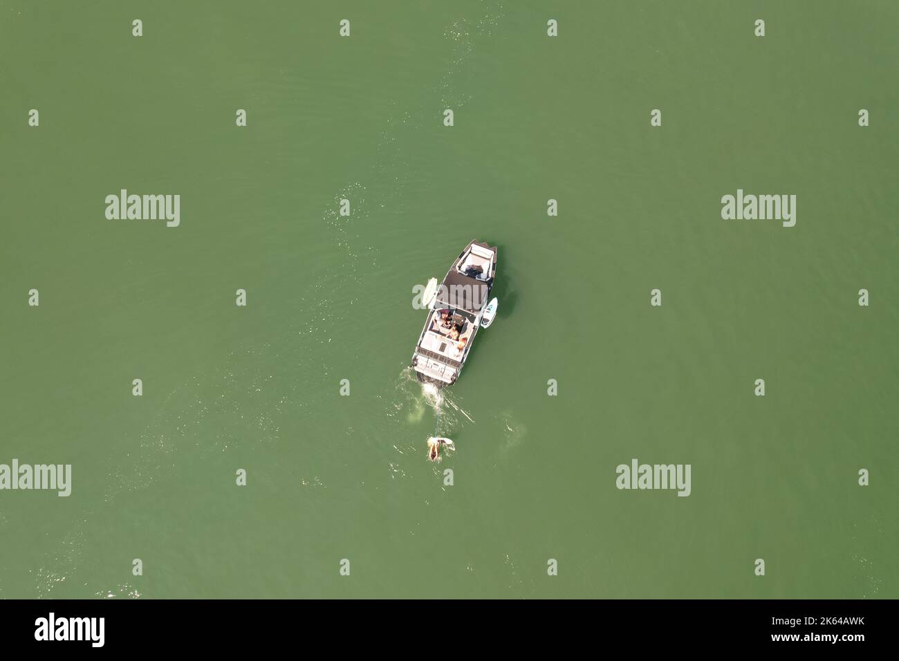 Vue de dessus d'un homme pratiquant le wakeboard remorqué par un hors-bord au milieu d'un lac. Banque D'Images