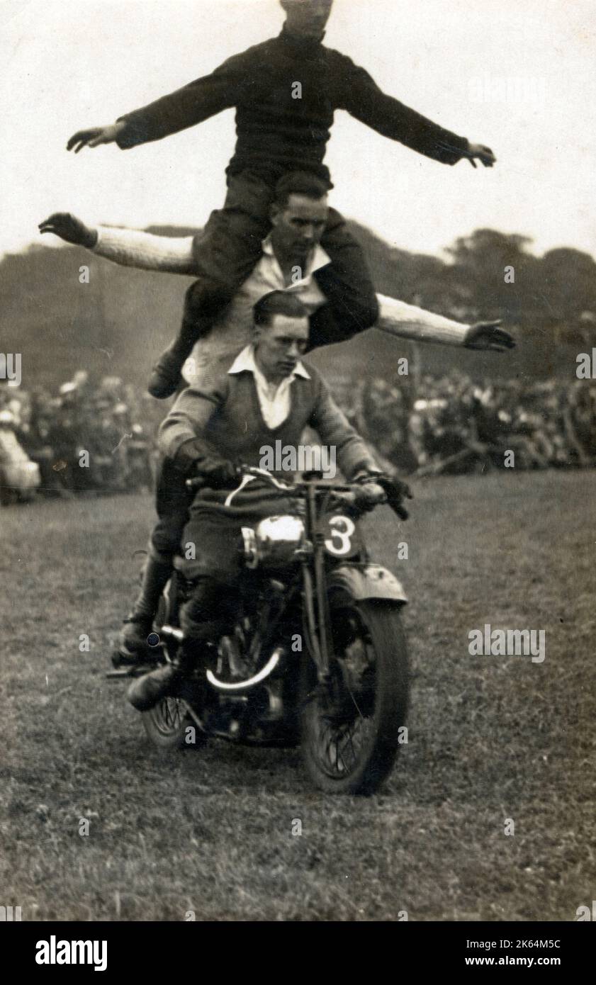 Une équipe d'affichage acrobatique de moto cascadeur - trois hommes sur un vélo... Banque D'Images