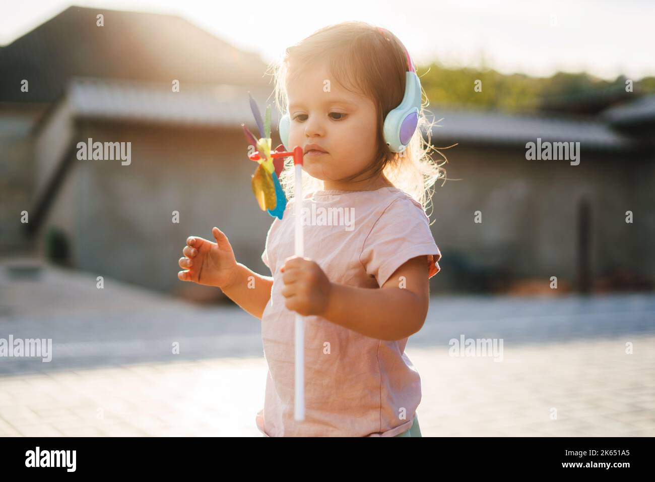 La fille debout dehors avec une weathervane dans sa main et regardant heureusement son nouveau jouet. Bonne santé de l'enfance et du bébé. Portrait de mignon Banque D'Images