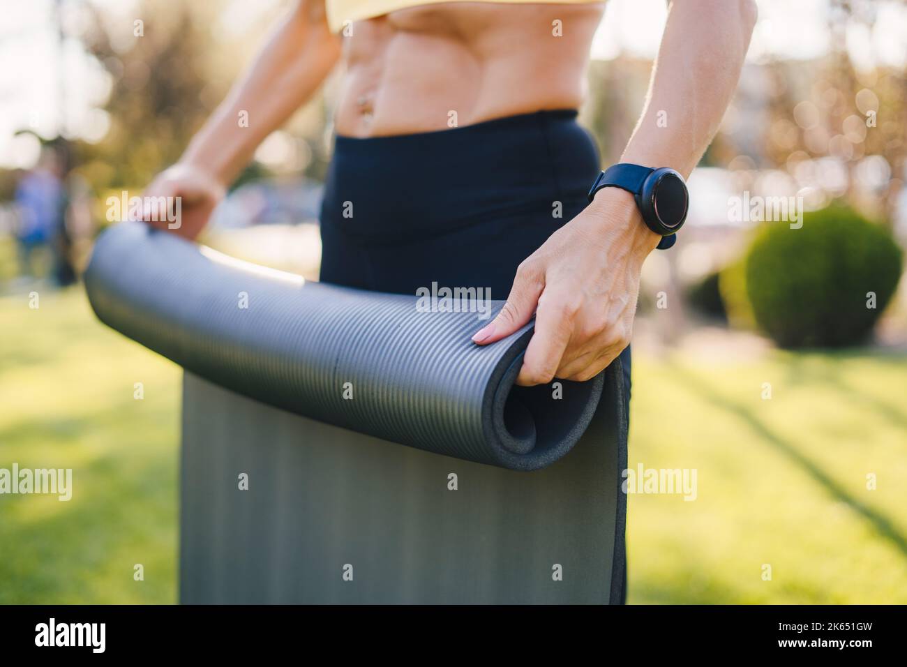 Tenue sportive jeune femme portant des vêtements de sport roulant yoga pilates tapis de caoutchouc à l'extérieur dans le parc. Mode de vie sain, sport. Entraînement. Jeune Banque D'Images