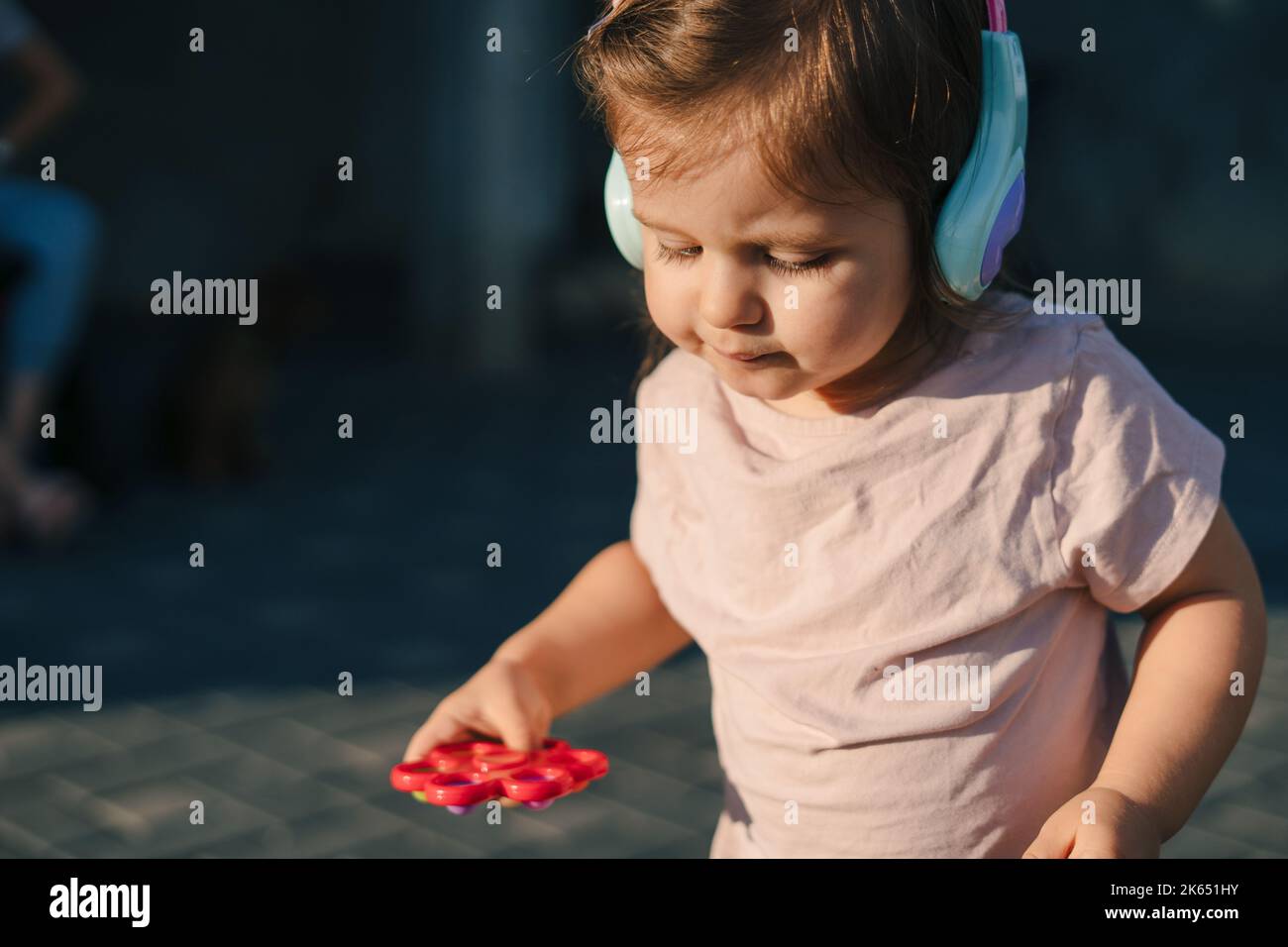 La jeune fille a passé du temps dehors en plein air, portant des bouchons d'oreille pour éviter de prendre un froid. Tout-petits jouant. Jour d'été ou d'automne Banque D'Images