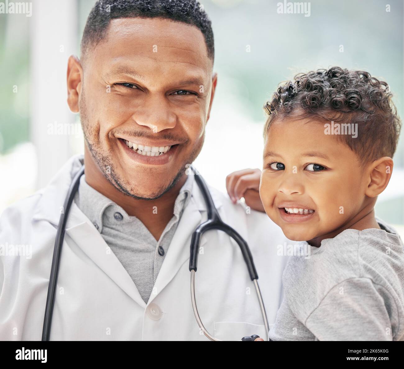 Portrait d'un beau jeune pédiatre noir tenant un adorable petit garçon dans les mains, un enfant mignon et un médecin souriant pendant le contrôle médical à la clinique Banque D'Images