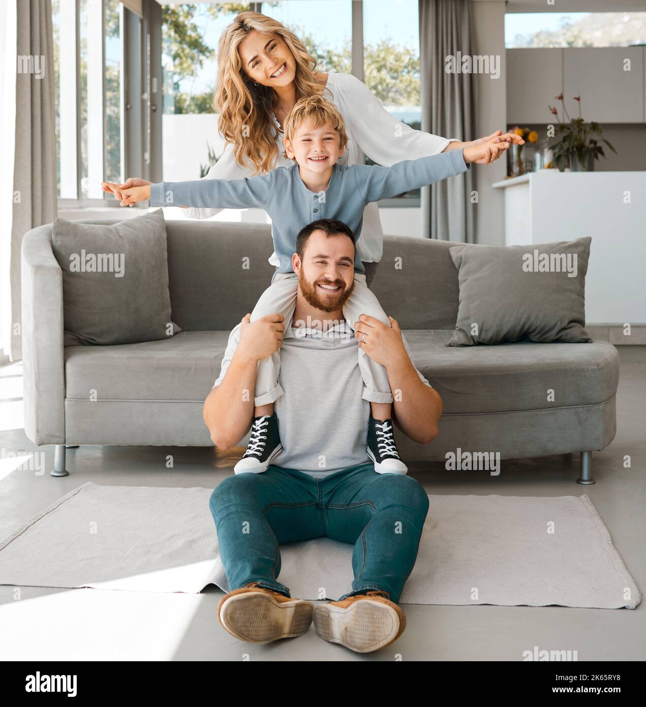 Portrait d'une famille heureuse. Parents et fils à la maison. Adorable garçon caucasien souriant et assis sur ses épaules de pères avec les bras étirés. Jeune Banque D'Images