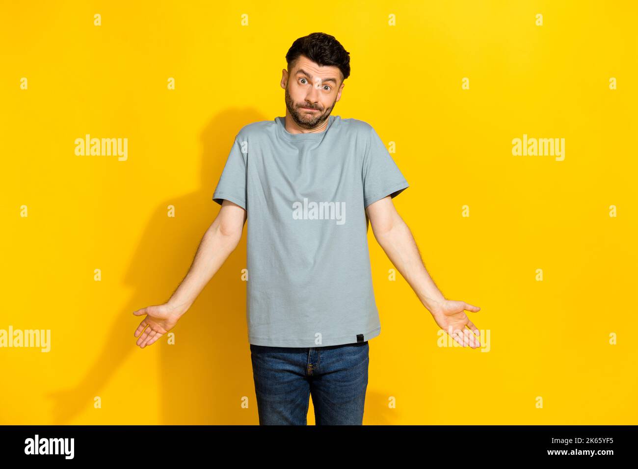 Photo de l'homme branché du millénaire brunet Bristle ne sais aucune idée haussement épaules ont oublié son argent à la maison avant le cinéma isolé sur la couleur jaune vif Banque D'Images