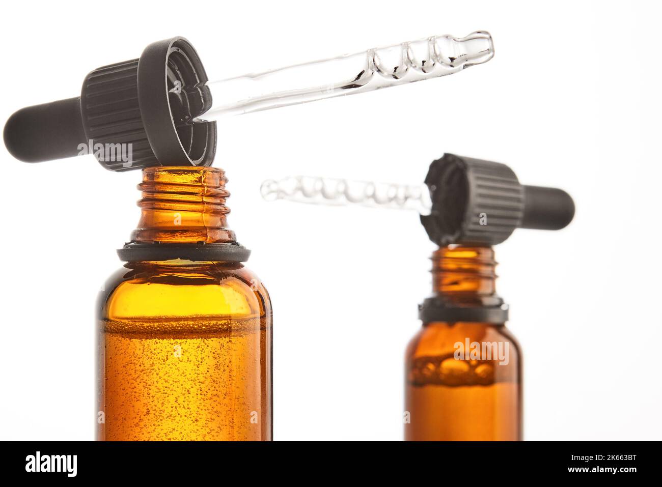 Deux pipettes avec sérum sont sur des cols de flacons ouverts bruns. Banque D'Images