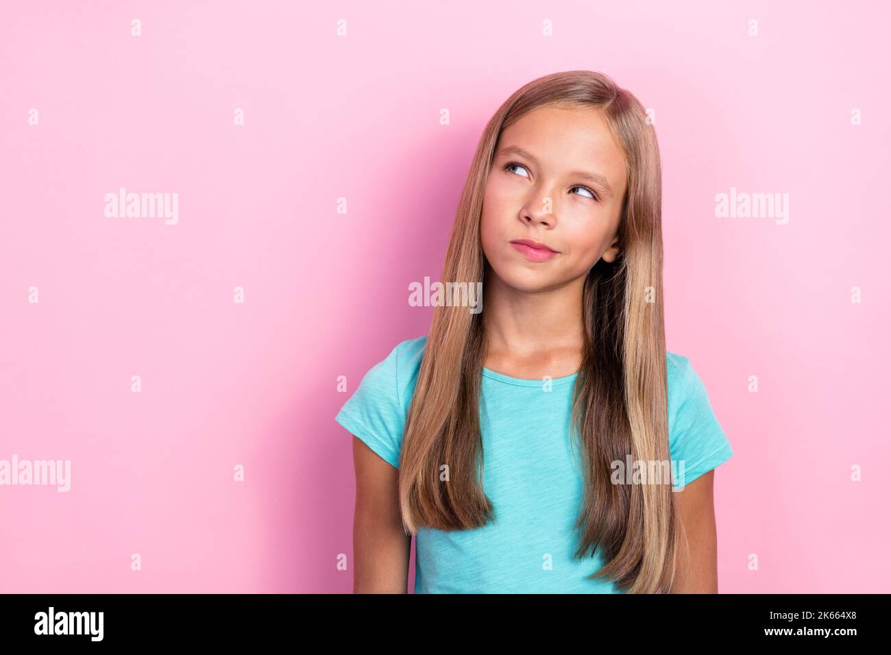 Photo de la petite fille de préteen intelligente peu d'esprit porter t-shirt bleu regardant les lèvres pouted ponder idée plan comment aller à la maison de l'école plus tôt isolé sur rose Banque D'Images