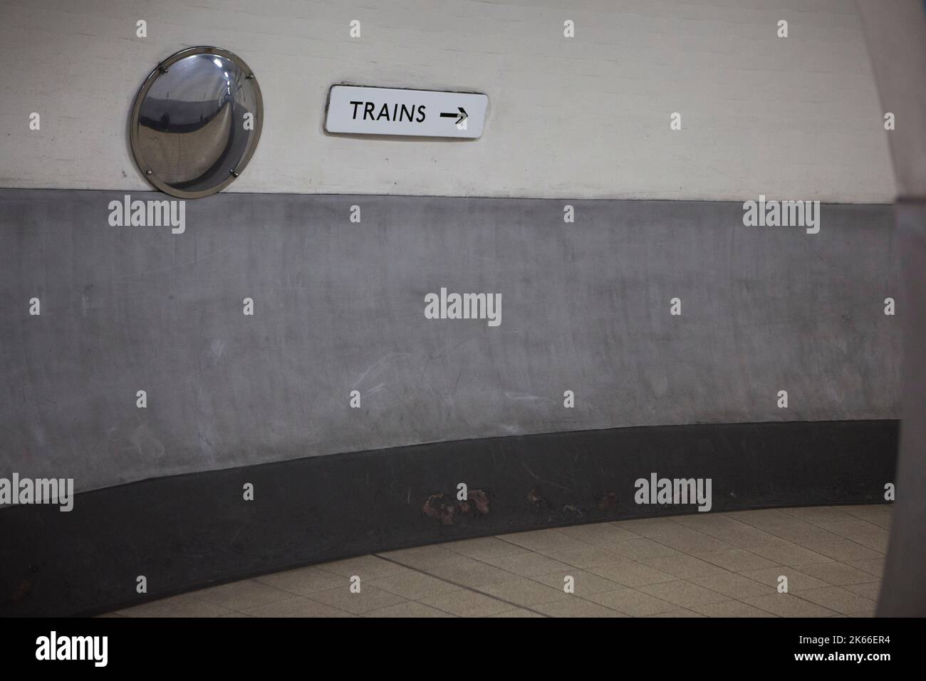 Un panneau indiquant « TRAINS » avec une flèche pointant vers la droite en bas d'un tunnel dans le métro à la station Holland Park sur la Central Line à l'ouest de Londres Banque D'Images